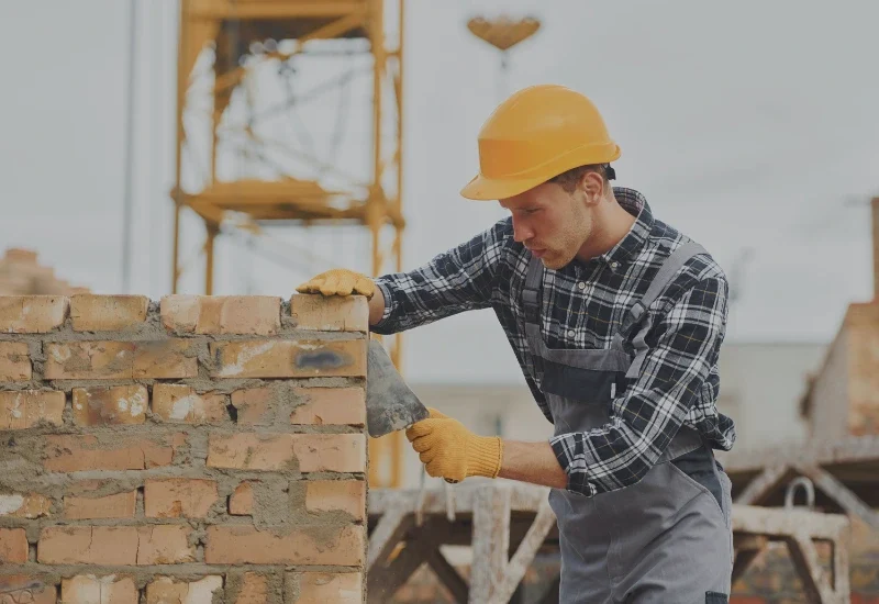 Profesjonalny murarz podczas murowania ściany z cegły.